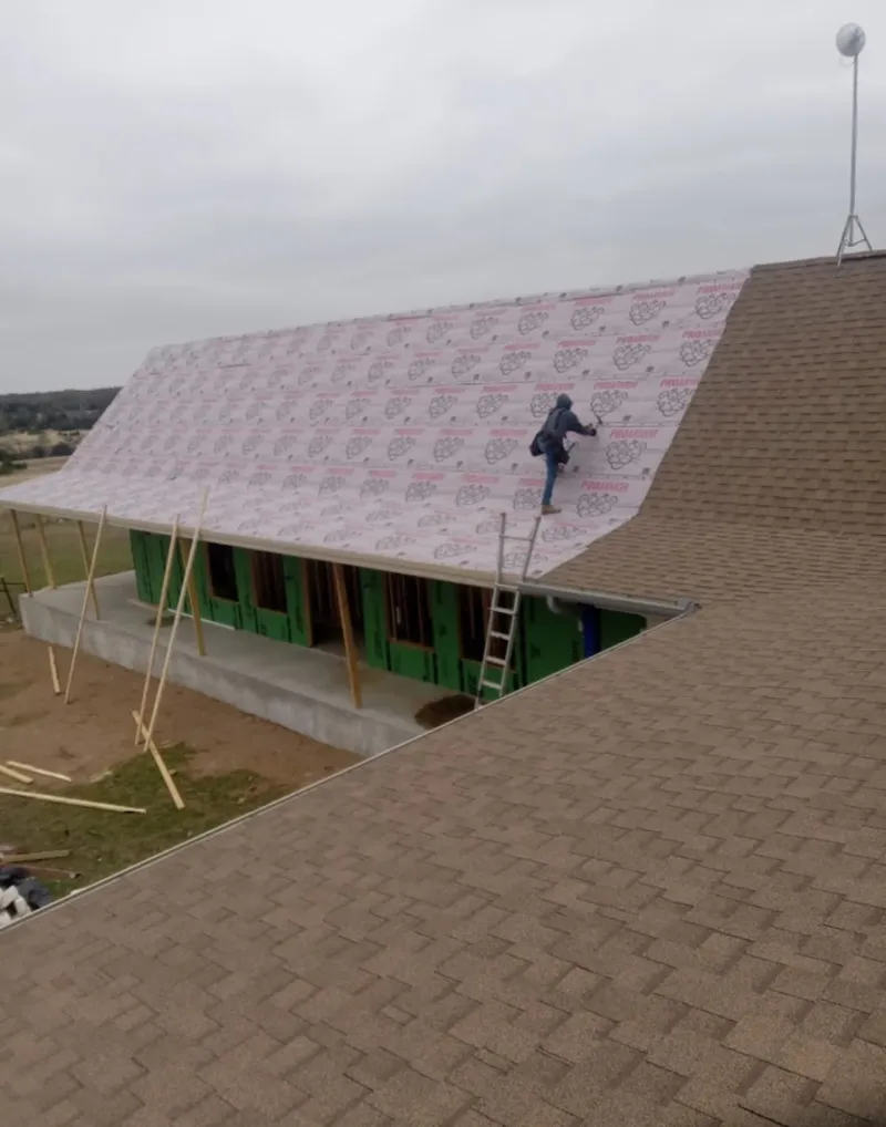 Worker preparing underlayment for a metal roof installation in Burley